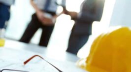 Blueprints and tools with business meeting background.