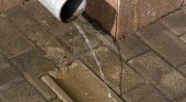 Water flowing from a pipe onto a stone pavement.